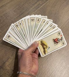 a person holding up several cards on top of a wooden table next to a hand