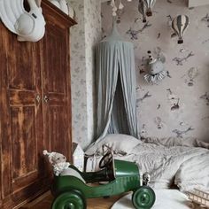 a green toy car sitting on top of a wooden floor next to a white bed