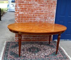 a wooden table sitting on top of a rug in front of a brick wall and blue door