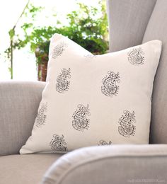 a white pillow sitting on top of a gray couch