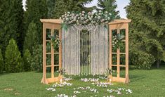 a wedding arch with flowers and greenery on the grass in front of some trees