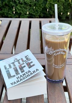 a cup of coffee sitting on top of a wooden table next to a stack of books