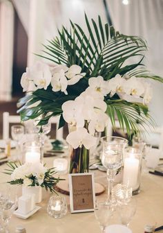 a centerpiece with white flowers and candles on a table