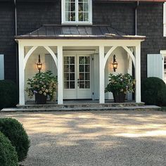 the front entrance to a large house with potted plants and lights on each side