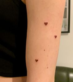 a woman's arm with small brown hearts on the left side of her arm