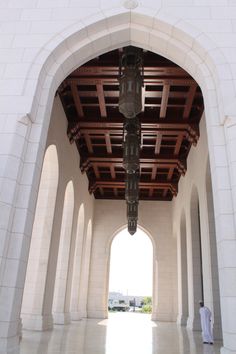 an archway leading into a white building with columns and arches on both sides, in the middle of a large room