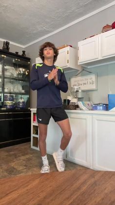 a man standing on top of a hard wood floor in front of a kitchen counter