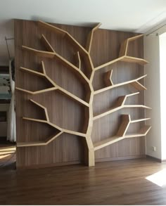 a wooden book shelf with shelves on the wall and a tree in the middle that has been carved into it