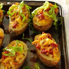 baked potatoes topped with cheese and lettuce on a baking sheet, ready to be eaten