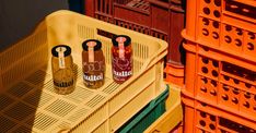 three bottles of wine sitting on top of a yellow crate in front of orange crates