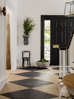 a black and white checkered floor with a potted plant on the wall next to it