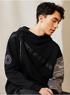 a young man sitting down wearing a black hoodie and sweatpants with his eyes closed