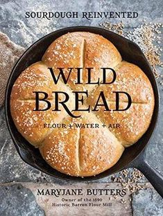 a cast iron skillet filled with bread on top of a stone counter next to an open book