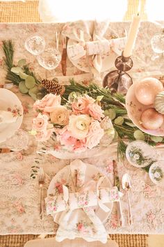 the table is set with pink flowers, pine cones and other things to decorate it