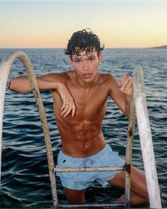 a shirtless young man sitting on top of a boat