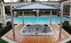 an outdoor hot tub in the middle of a wooden deck next to a swimming pool