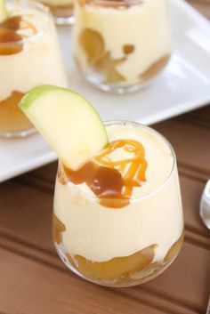 two desserts with apples and caramel sauce in glasses on a wooden table next to utensils