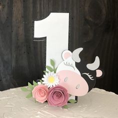 a birthday cake with a cow and flowers on the top is decorated in pink, white, and black