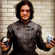 a man wearing a leather jacket holding two small figurines