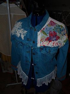 a blue jean jacket with white lace and flowers on it