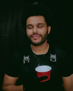 a man wearing a black shirt with a red and white cup on it's chest