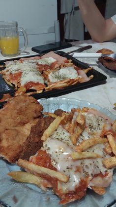 two trays of food on a table, one with french fries and the other with meat