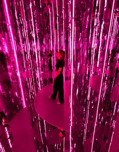 two people are standing in front of a pink wall with lots of lights on it