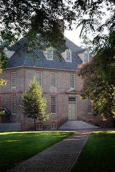 an old brick building with trees and grass around it