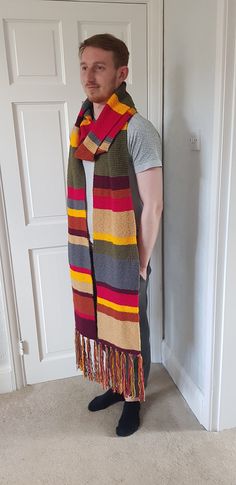 a man standing in front of a door wearing a multicolored striped scarf with fringes