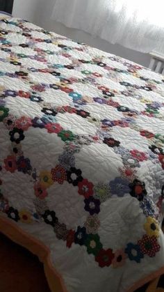 a bed with a quilt on top of it next to a wooden headboard and window