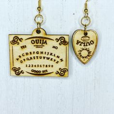 two wooden earrings hanging from hooks on a white background with words written in cursive writing