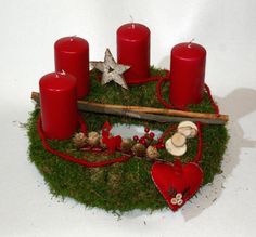 some red candles sitting on top of a moss covered circle with other items around it