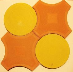 three orange and yellow plates sitting on top of a white countertop next to each other