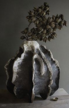 a vase filled with flowers sitting on top of a wooden table next to a wall