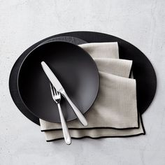 a black plate with silverware on top of it next to a napkin and fork