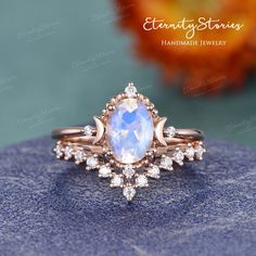 an engagement ring with a rainbow colored stone surrounded by white and pink diamonds on a blue surface