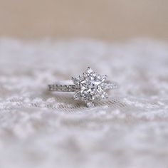 a diamond ring sitting on top of a lace covered surface