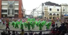 a group of people that are standing in the street with some green costumes on them