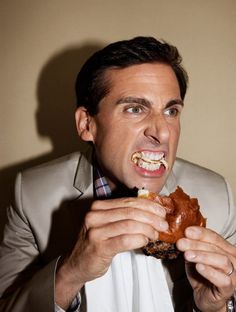 a man in a suit eating food with his mouth open