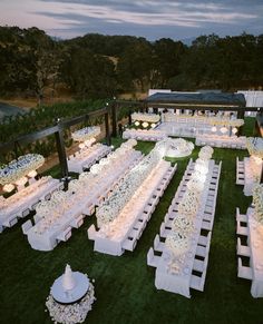 an aerial view of a wedding reception setup with white flowers and centerpieces on the grass