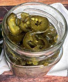 pickles are in a glass jar on a napkin