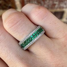 a woman's hand holding a ring with green and white stones on the inside