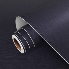 a roll of dark blue paper with white stripes on the bottom and sides, laying on a black surface