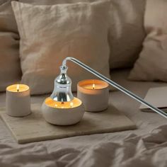 three lit candles sit on a tray next to a lamp