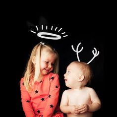 two young children sitting next to each other in front of a black background with white letters