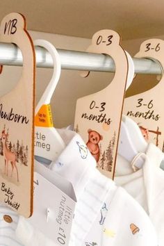 three baby bibs hanging from a rail with numbers and animals on them, along with other bibs