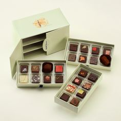 three boxes filled with different types of chocolates on top of a white table next to each other