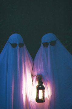 two ghost like figures holding a lantern in their hands