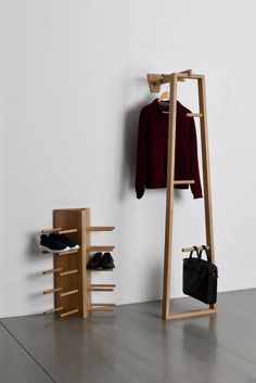 a coat rack with shoes and handbag next to it on the floor in front of a white wall