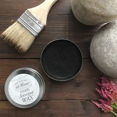 two tins and a brush sitting on top of a wooden table next to some flowers